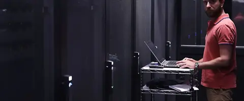 Tecnico Host.it al lavoro con il portatile tra i rack del datacenter